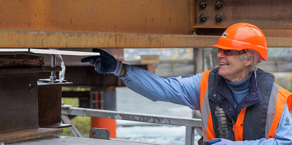 A worker holding a steel beam and smiling