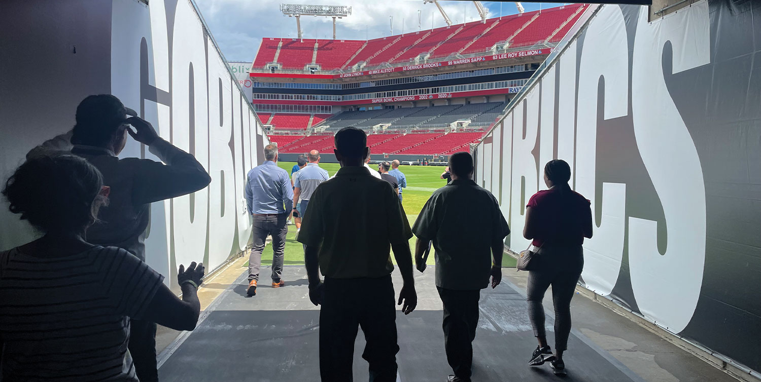 people walk out onto the field from an entry way at the Raymond James Stadium