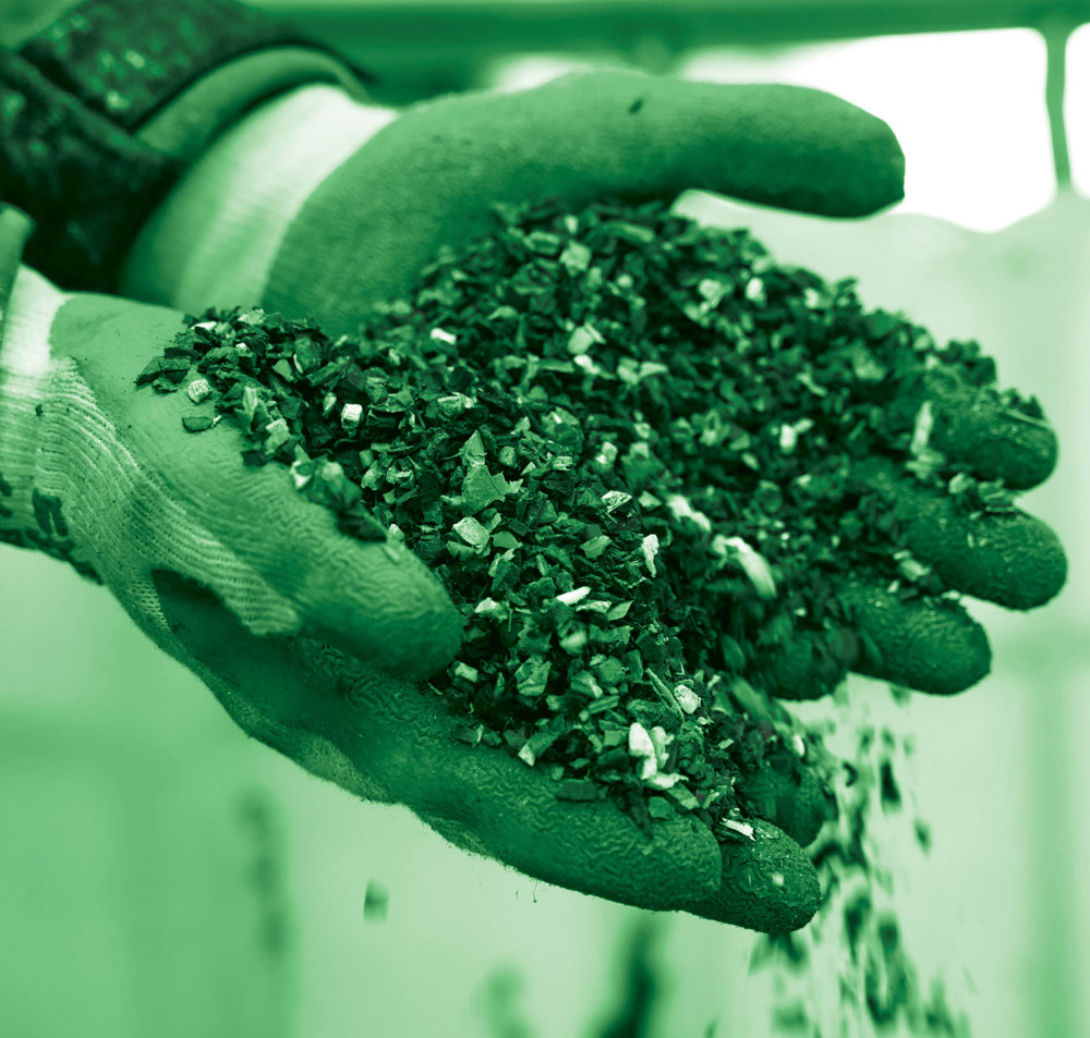 hands in gloves holding tiny pieces of recycled plastics