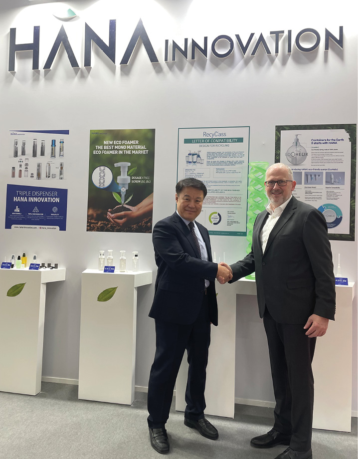 two men shake hands in front of HANA INNOVATION