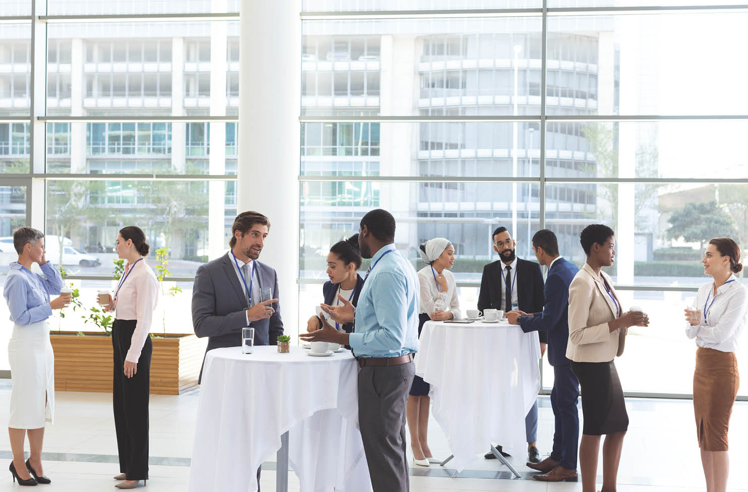 well dressed professionals networking with drinks in their hand around tables