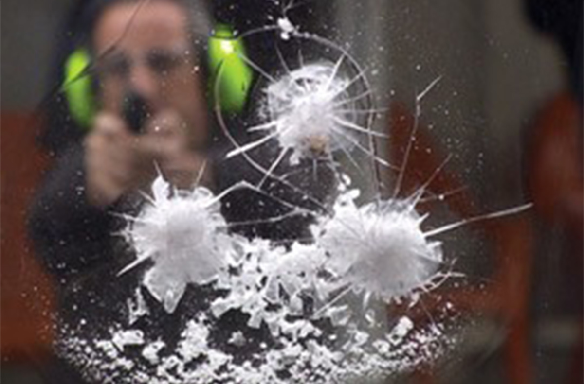 person shooting a gun into laminated polycarbonate