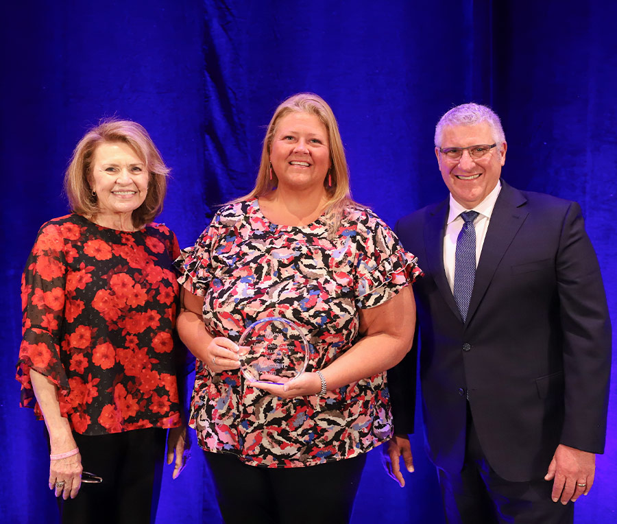 Katie Clapp standing between Deborah Ragsdale and Peter DelGado and holding an award