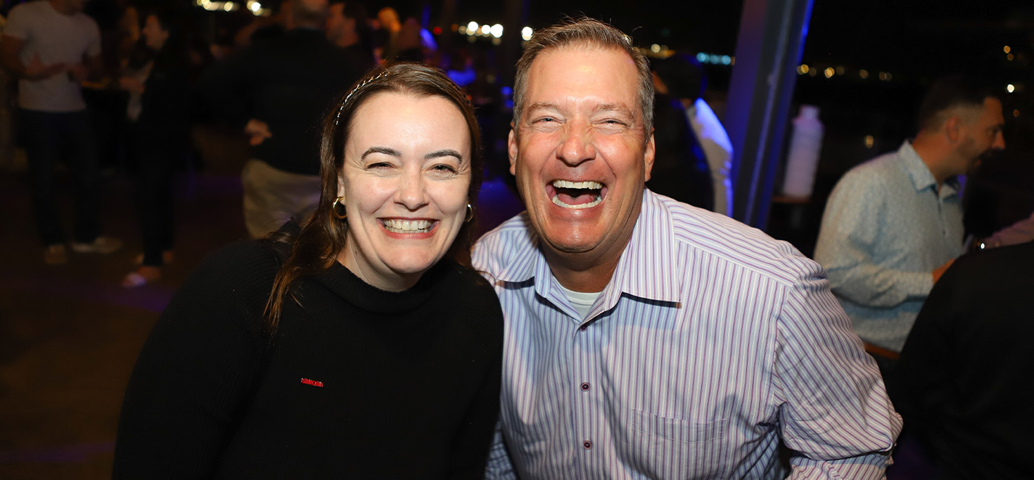 a man and a woman smile brightly together while enjoying the closing party at Coasterra