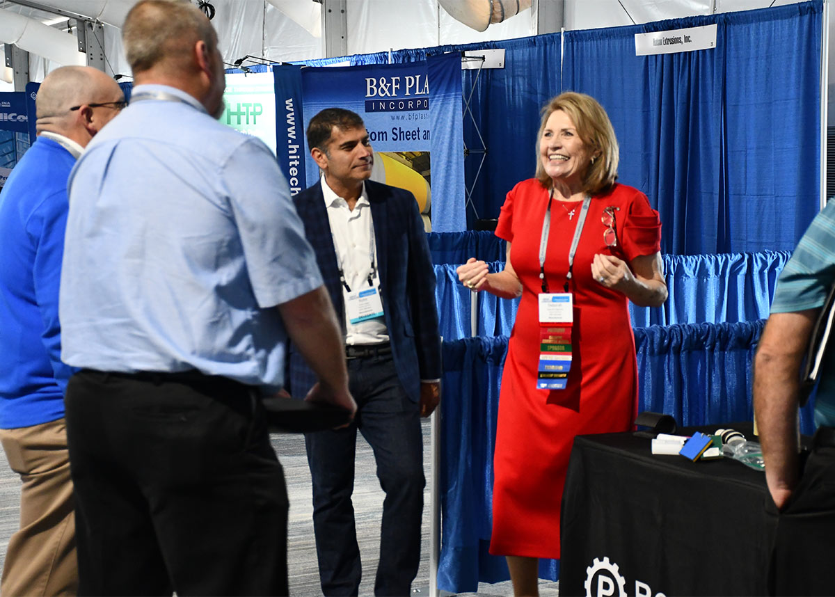  former IAPD president Deborah Ragsdale speaks to connecX trade show while standing beside a Polymer Industries table