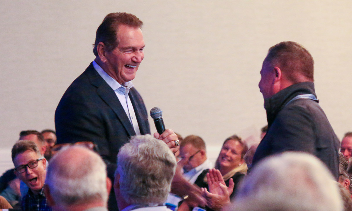 two men shake hands among an cheering audience at the 67th Annual IAPD Convention