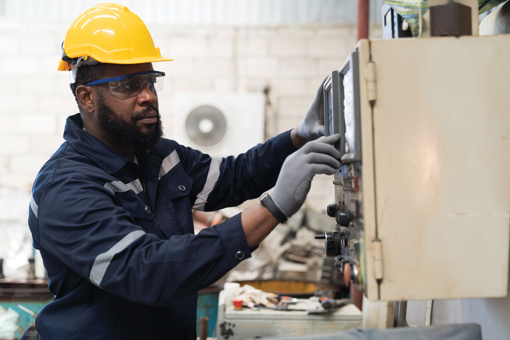 man in a yellow hard hat working on a machine in a factory