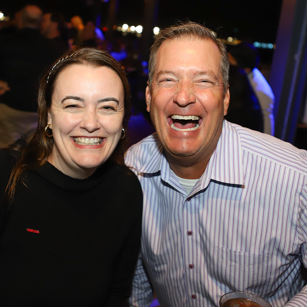 a female and a male attendee smile for the camera at a social event