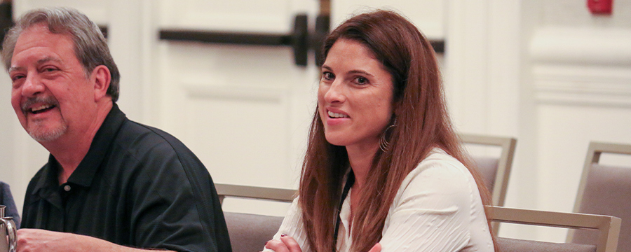 cropped view of a man and a woman pictured at a supplier meeting held in a large conference room