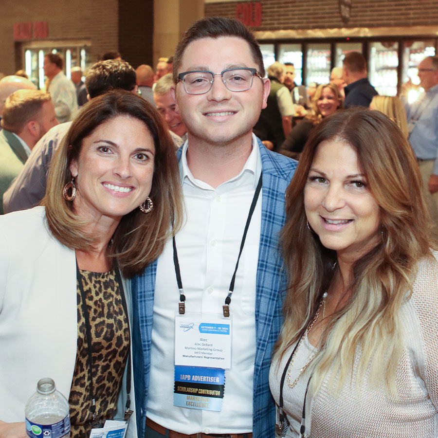Three people smiling for a photo at an indoor reception event.