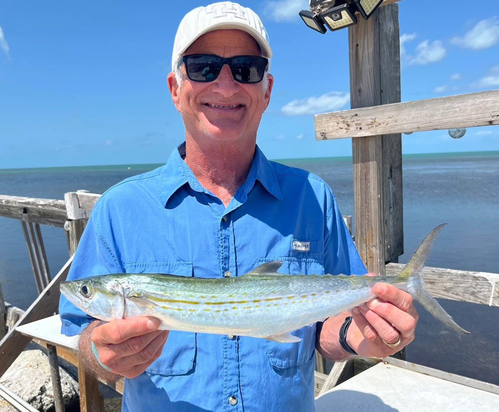 close up of Elliot Dworkin smiling while holding a caught fish on a boat