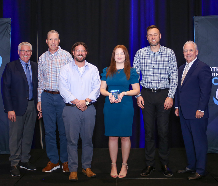 Four Roechling Industrial representatives pose between two presenters against a blue backdrop.