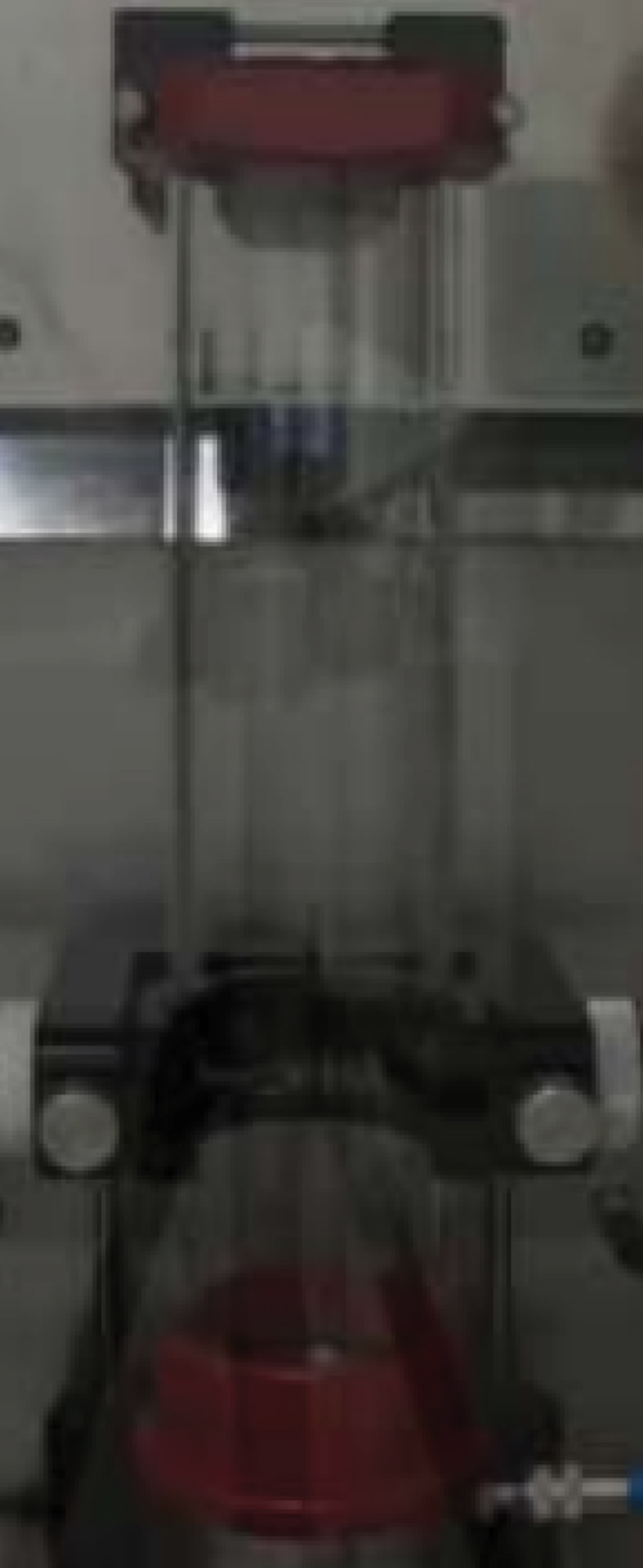 An industrial laboratory setup featuring a vertical glass tube furnace used for testing the minimum ignition temperature of dust clouds in a controlled environment.