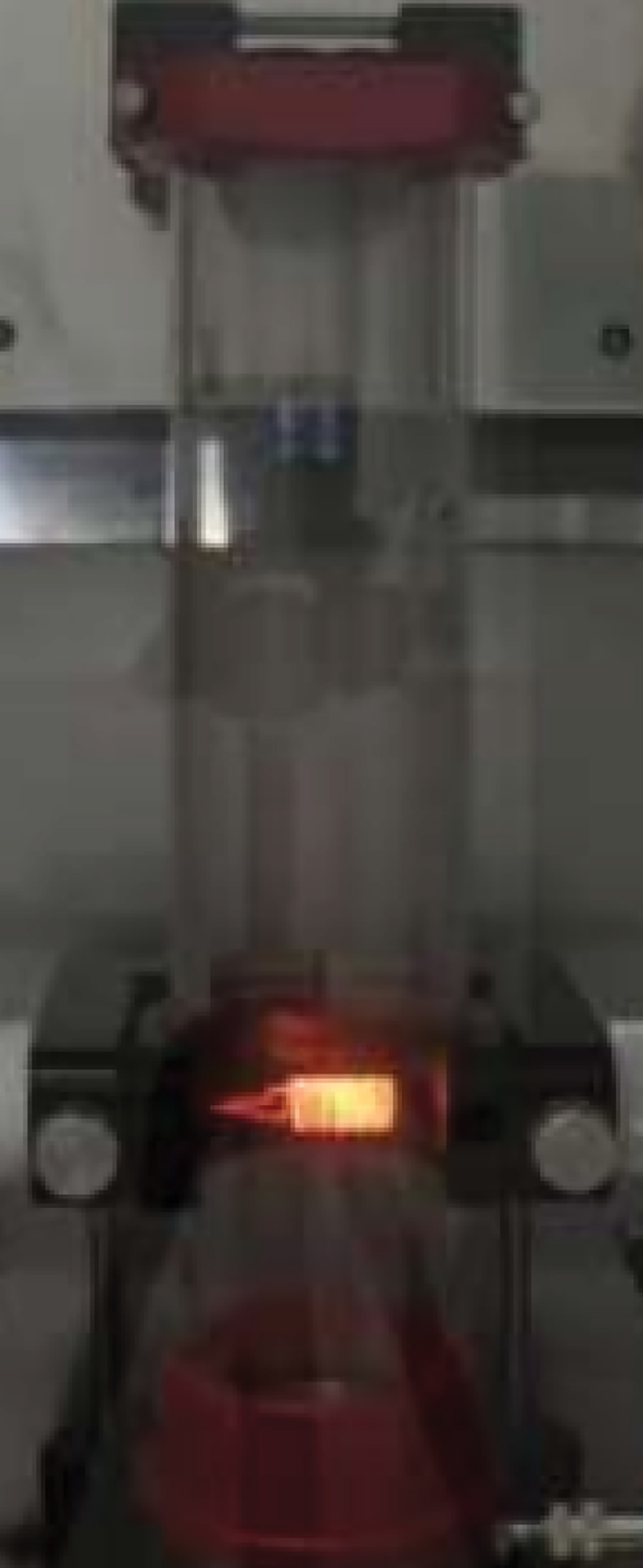 A testing sequence in a glass tube furnace where a small, bright spark or ignition source is introduced to a sample to evaluate the combustibility of industrial dust.