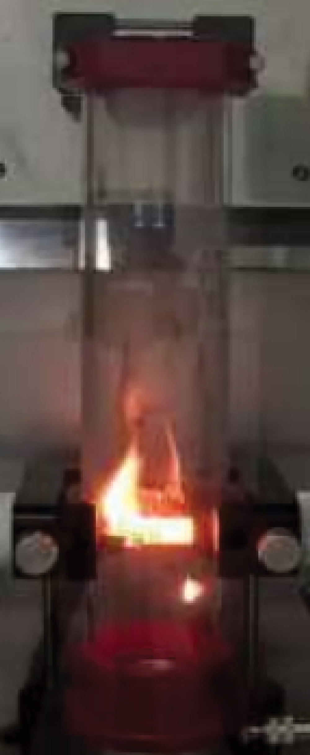 A laboratory combustion test showing a visible orange flame spreading through a vertical glass tube, demonstrating the high flammability of a specific dust sample.