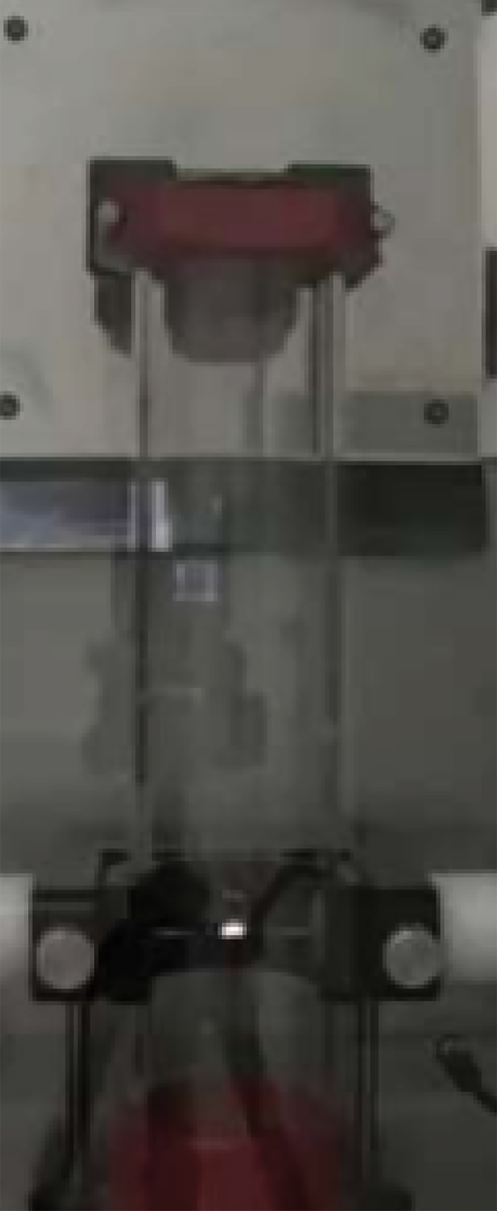 A wide view of a dust explosion testing apparatus, consisting of a vertical glass cylinder held in a metal frame, used to determine the explosive potential of materials.