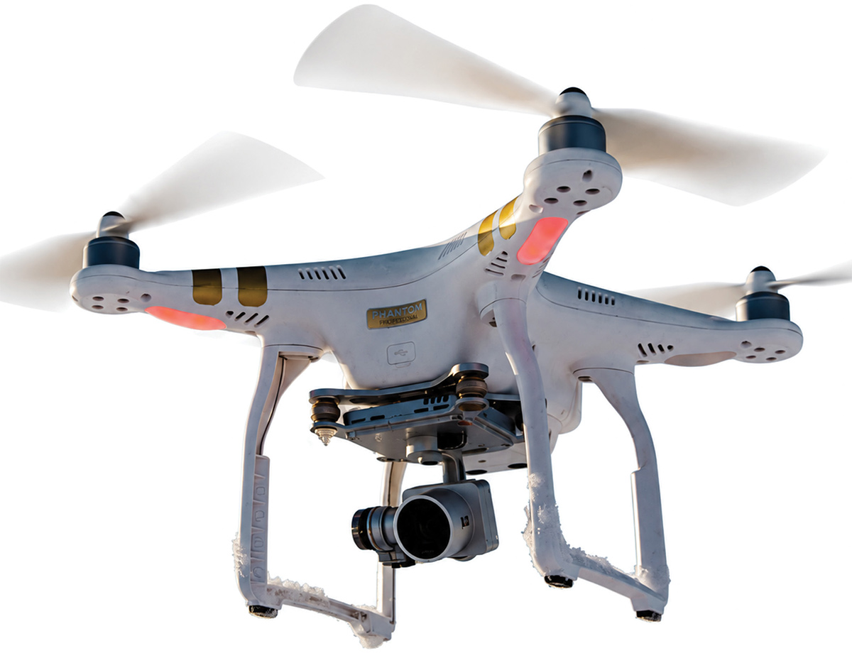 A white Phantom quadcopter drone hovering with spinning propellers against a bright background