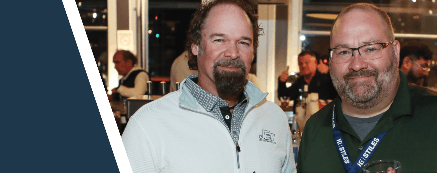 A horizontal composite image showing two men posing for a photo against a dark blue background slice at a conference reception.