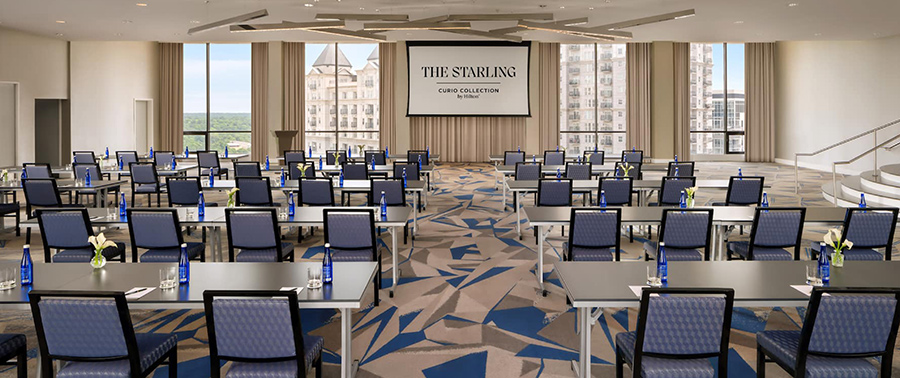 An empty modern conference room setup with tables, chairs, and a projection screen.