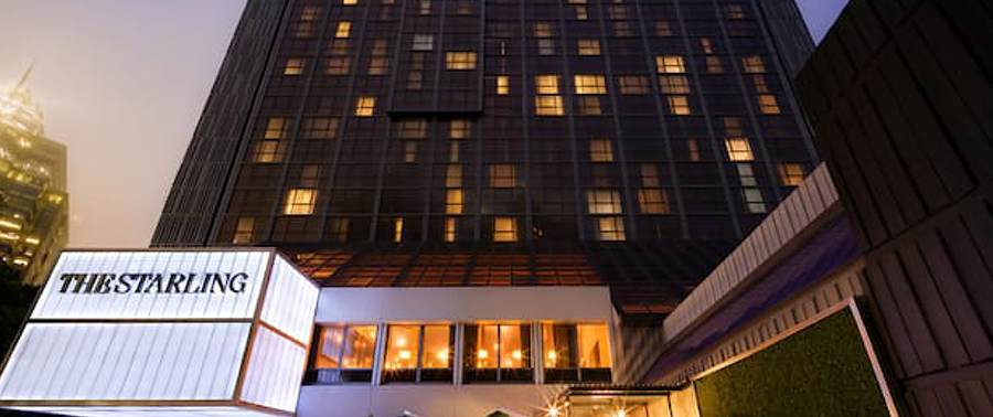 Exterior view of The Starling hotel building at night with lit windows.