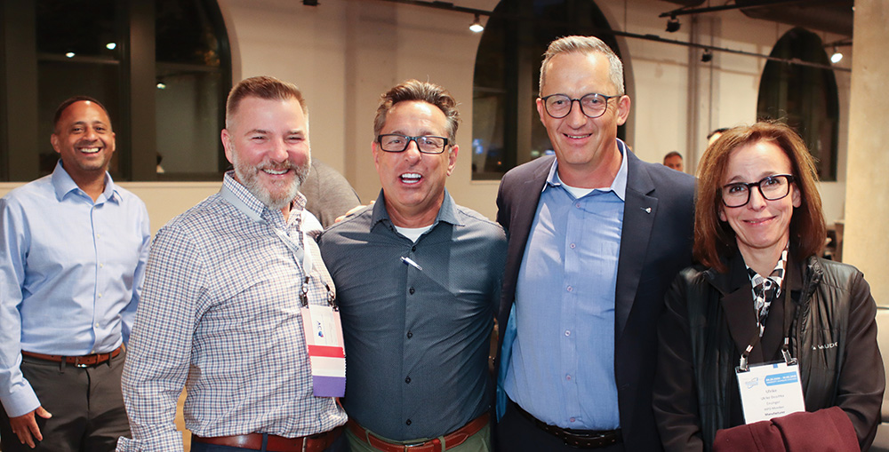 A group of five professionals posing and smiling together at a conference event.