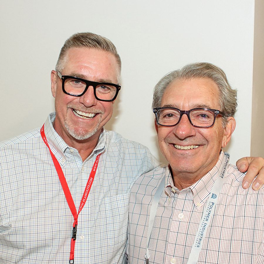 Two men in eyeglasses smiling while posing closely together.