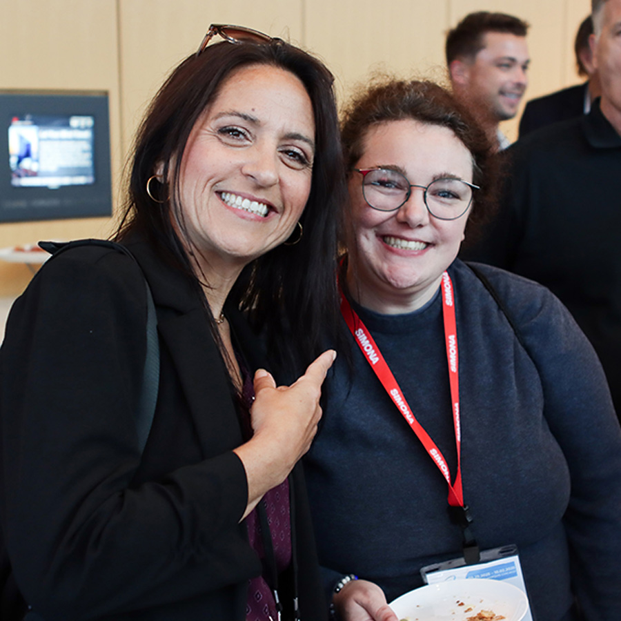 Two women smiling and posing at an event while holding a plate.